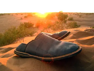 a shoe sitting on the sand in the desert at Le Drom'blanc in Mhamid