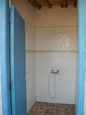 a shower in a bathroom with a blue door at Le Drom'blanc in Mhamid