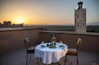 a table and chairs on a balcony with the sunset at Dar Bladi in Ouarzazate