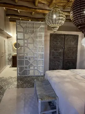 a bedroom with a bed and two chandeliers at Ksar Ighnda in Aït Ben Haddou