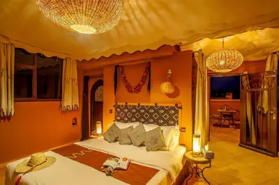 a bedroom with a large bed with orange walls at Ksar Ighnda in Aït Ben Haddou