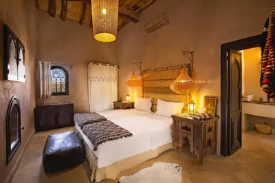 a bedroom with a bed and a table and a lamp at Ksar Ighnda in Aït Ben Haddou