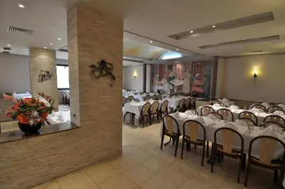 a restaurant with white tables and chairs in a room at Hôtel Wassim in Fès