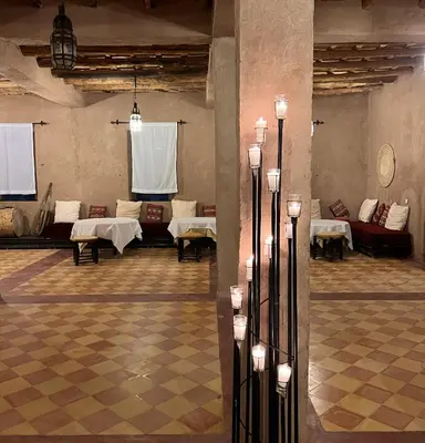 a large room with tables and couches in it at Kanz Erremal in Merzouga