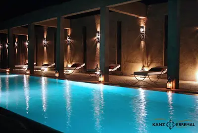 a swimming pool at night with chairs and lights at Kanz Erremal in Merzouga