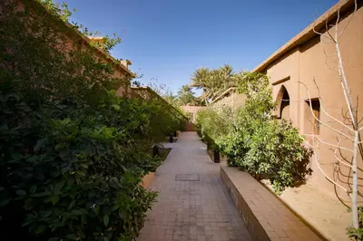 a brick alley with plants on the side of a building at Kanz Erremal in Merzouga