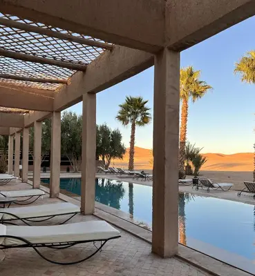 a resort with a pool and palm trees at Kanz Erremal in Merzouga