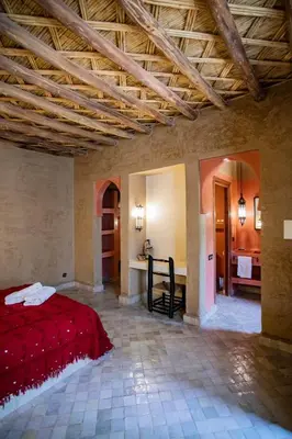 a bedroom with a red bed in a room at Kanz Erremal in Merzouga