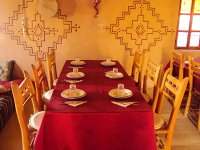 a long table with a red table cloth and chairs at Dar Timitar in Kalaat MGouna