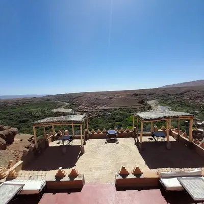 a patio with tables and chairs and a view of the desert at Dar Timitar in Kalaat MGouna