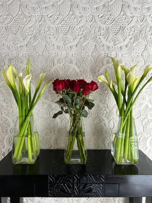 three vases with roses in them on a table at Dar Tazi - Medina View in Fès