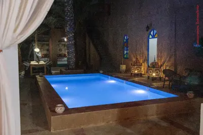 a large blue swimming pool in a room at Hotel Riad Sahara Activity in Mhamid