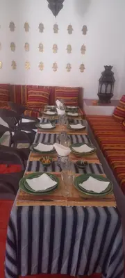 a long table with plates and glasses on it at Hotel Riad Sahara Activity in Mhamid