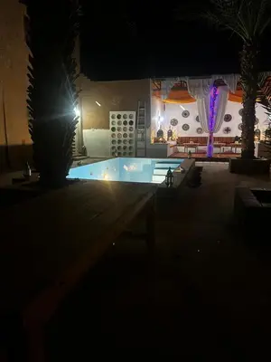 a swimming pool at night with a lit up building at Hotel Riad Sahara Activity in Mhamid