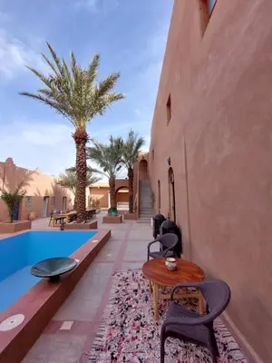 a patio with a table and chairs next to a pool at Hotel Riad Sahara Activity in Mhamid
