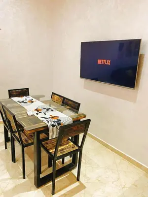 a table with chairs and a television on a wall at Appartement calme in Fès