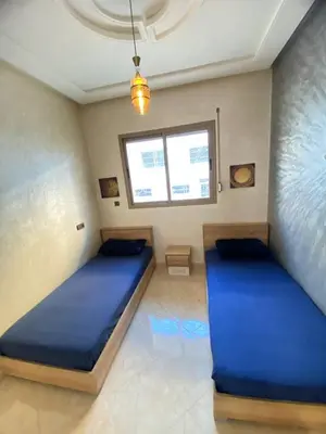 two beds in a room with blue sheets and a window at Appartement calme in Fès