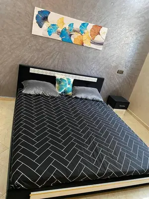 a bedroom with a bed with a black comforter at Appartement calme in Fès