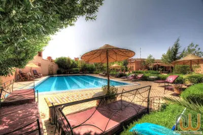 a swimming pool with an umbrella and chairs and a pool at La Perle Du Dades in Boumalne