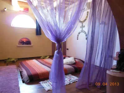 a bedroom with a bed with purple curtains at La Perle Du Dades in Boumalne