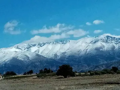 a snow covered mountain in front of a field at Auberge Ouabas in Agoudim