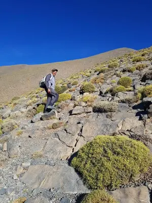 a man with a backpack walking on a rocky mountain at Auberge Ouabas in Agoudim