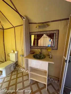 a bathroom with a sink and a mirror and a toilet at Merzouga heart camp in Merzouga