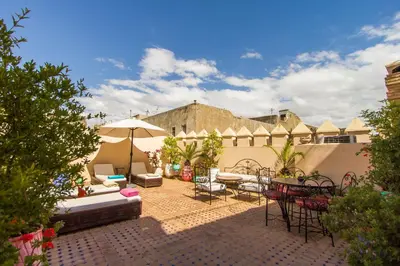 a patio with chairs and tables and an umbrella at Riad Fes Baraka & SPA in Fès