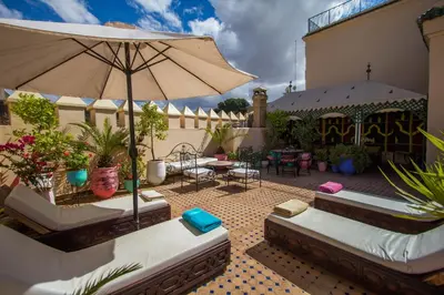 a patio with two couches and an umbrella at Riad Fes Baraka & SPA in Fès
