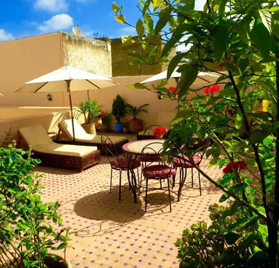 a patio with a table and chairs and an umbrella at Riad Fes Baraka & SPA in Fès