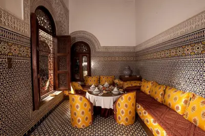 a living room with a table and yellow chairs at Riad Alya in Fès