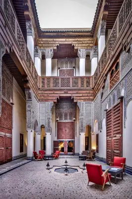 a large room with red chairs and a fireplace at Hotel & Spa Dar Bensouda in Fès