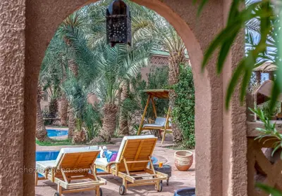 a group of lawn chairs and a person laying on a swing at Chez Le Pacha - Authentic Sahara Hotel Mhamid in Mhamid