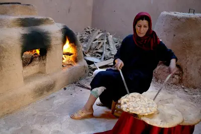 a woman is sitting in front of an oven at Chez Le Pacha - Authentic Sahara Hotel Mhamid in Mhamid