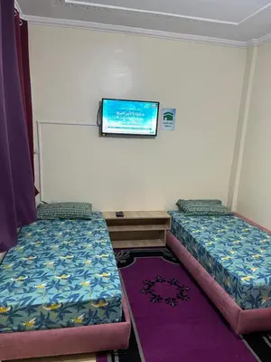 a room with two beds and a tv on the wall at Chez ZAKi in Meknès