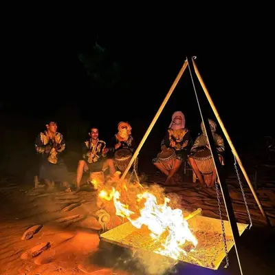 a group of people sitting around a fire at Maktub Desert Luxury Camp in Merzouga