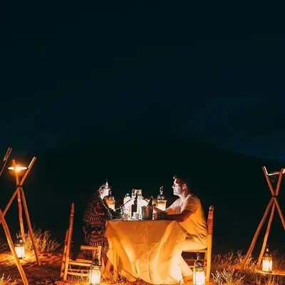 two people sitting at a table at night at Maktub Desert Luxury Camp in Merzouga