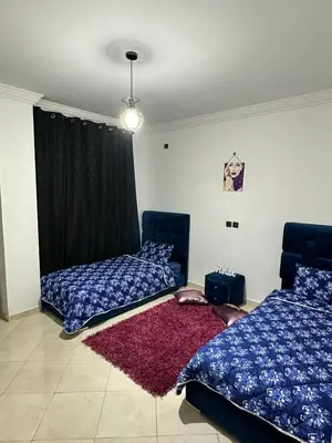 a bedroom with two beds and a red rug at Appartement à beni mellal in Beni Mellal