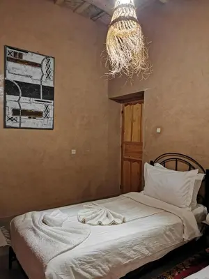 a bedroom with a bed and a chandelier at Maison d'hôte tamatart - Homestay in Kalaat MGouna