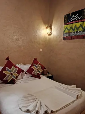 a bedroom with a bed with red and white pillows at Maison d'hôte tamatart - Homestay in Kalaat MGouna