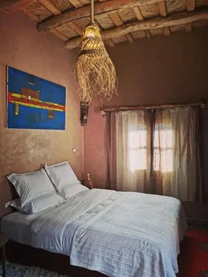a bedroom with a bed and a chandelier at Maison d'hôte tamatart - Homestay in Kalaat MGouna