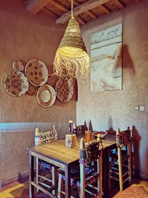 a dining room with a wooden table and a chandelier at Maison d'hôte tamatart - Homestay in Kalaat MGouna