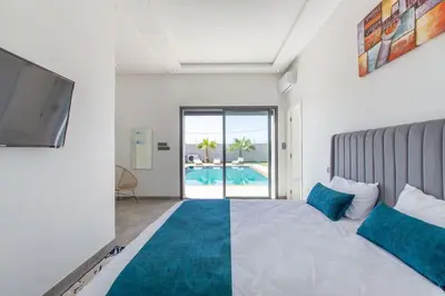 a bedroom with a bed and a tv and a pool at Villa Coquelicot, modern style avec jacuzzi, piscine Chauffée in Marrakech