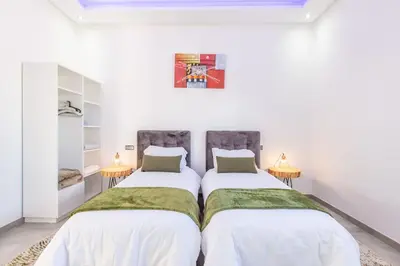 two beds in a room with white walls at Villa Coquelicot, modern style avec jacuzzi, piscine Chauffée in Marrakech