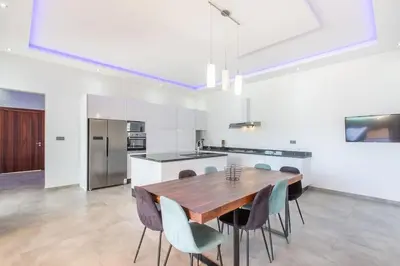 a kitchen and dining room with a wooden table and chairs at Villa Coquelicot, modern style avec jacuzzi, piscine Chauffée in Marrakech