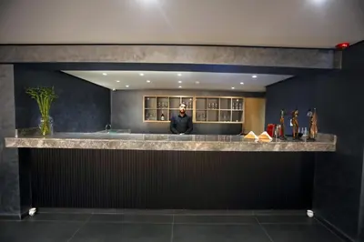 a man standing behind a bar in a room at HOTEL BELLE VUE MEKNES in Meknès