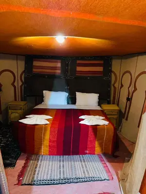 a bedroom with a large bed with a colorful blanket at Glance over nights at luxury in Merzouga