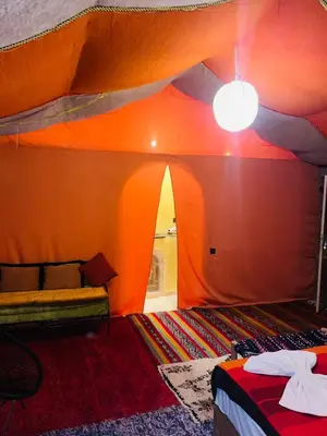 an orange tent with a bed and a lamp at Glance over nights at luxury in Merzouga