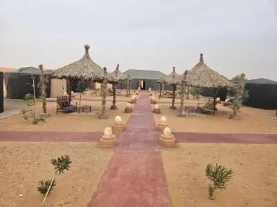 a pathway in the desert with umbrellas and tables at Glance over nights at luxury in Merzouga