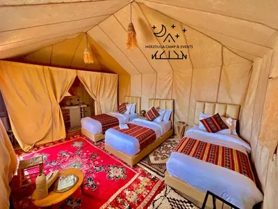 a group of four beds in a tent at Merzouga Camp & Events in Merzouga